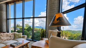 A spacious room with large windows, a sofa, a wooden coffee table, and a lamp. - Sugartop Resort 6th-Floor Corner Condo: Breathtaking Mountain Views - 2BR (Sugar Mountain)