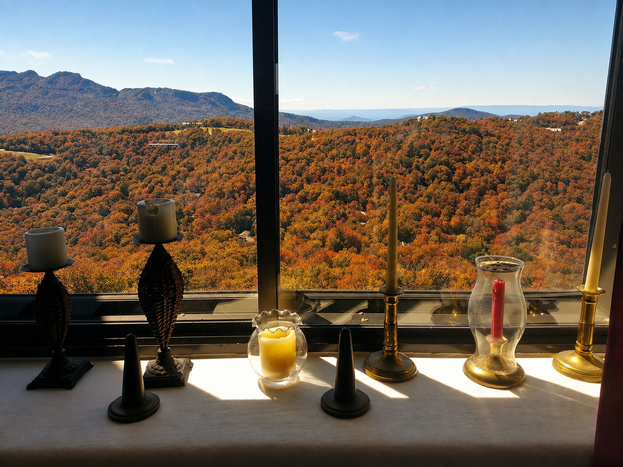 Une table décorée de bougies, avec vue sur une chaîne de montagnes boisée.