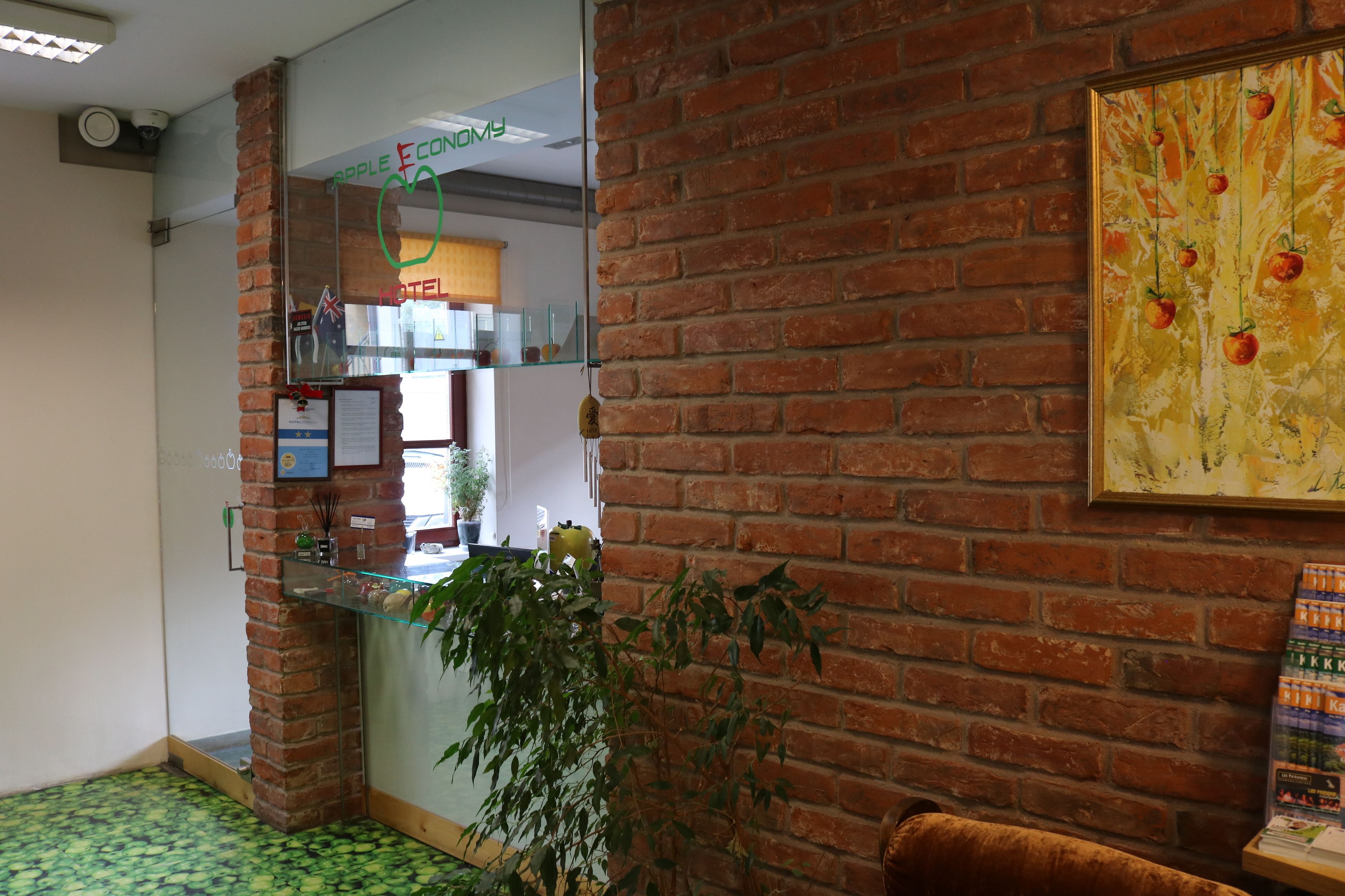 A reception area with a brick wall, a glass display case, a plant, and a framed artwork.