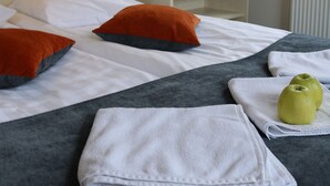 A hotel room with a bed, pillows, a nightstand with a plant, and a window with a view. - Apple Economy Hotel (Kaunas)