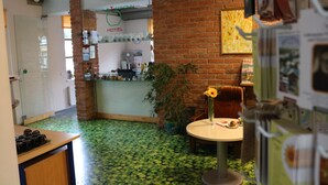 A hotel lobby with a green patterned floor, a brick wall, a reception desk, and a dining area with a table and chairs. - Apple Economy Hotel (Kaunas)