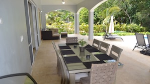 A covered outdoor dining area with a glass table, cushioned chairs, and a view of a lush garden. - THIS IS IT!!!!!! Newly built Renters Paradise (Sosua)
