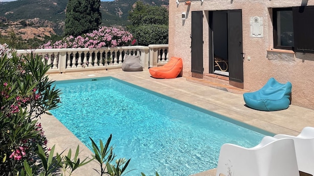 Un espace piscine offrant une vue dégagée sur les montagnes, un bâtiment doté d’un balcon et quelques coins salon.