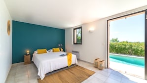 Une chambre à coucher avec un lit, des tables de chevet, une fenêtre et une vue sur une piscine.