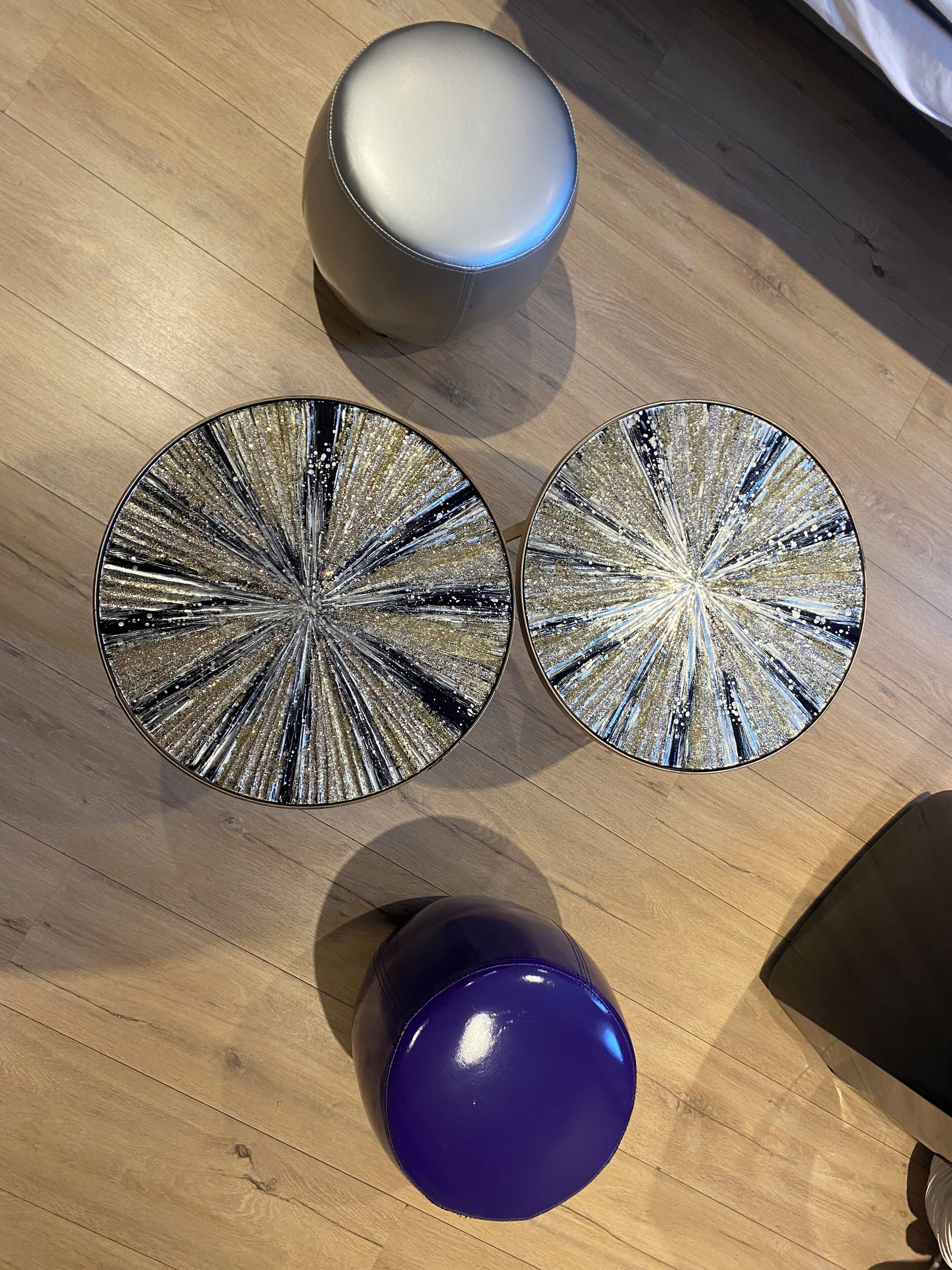 A round table with a reflective, metallic surface and a blue object in front of it.