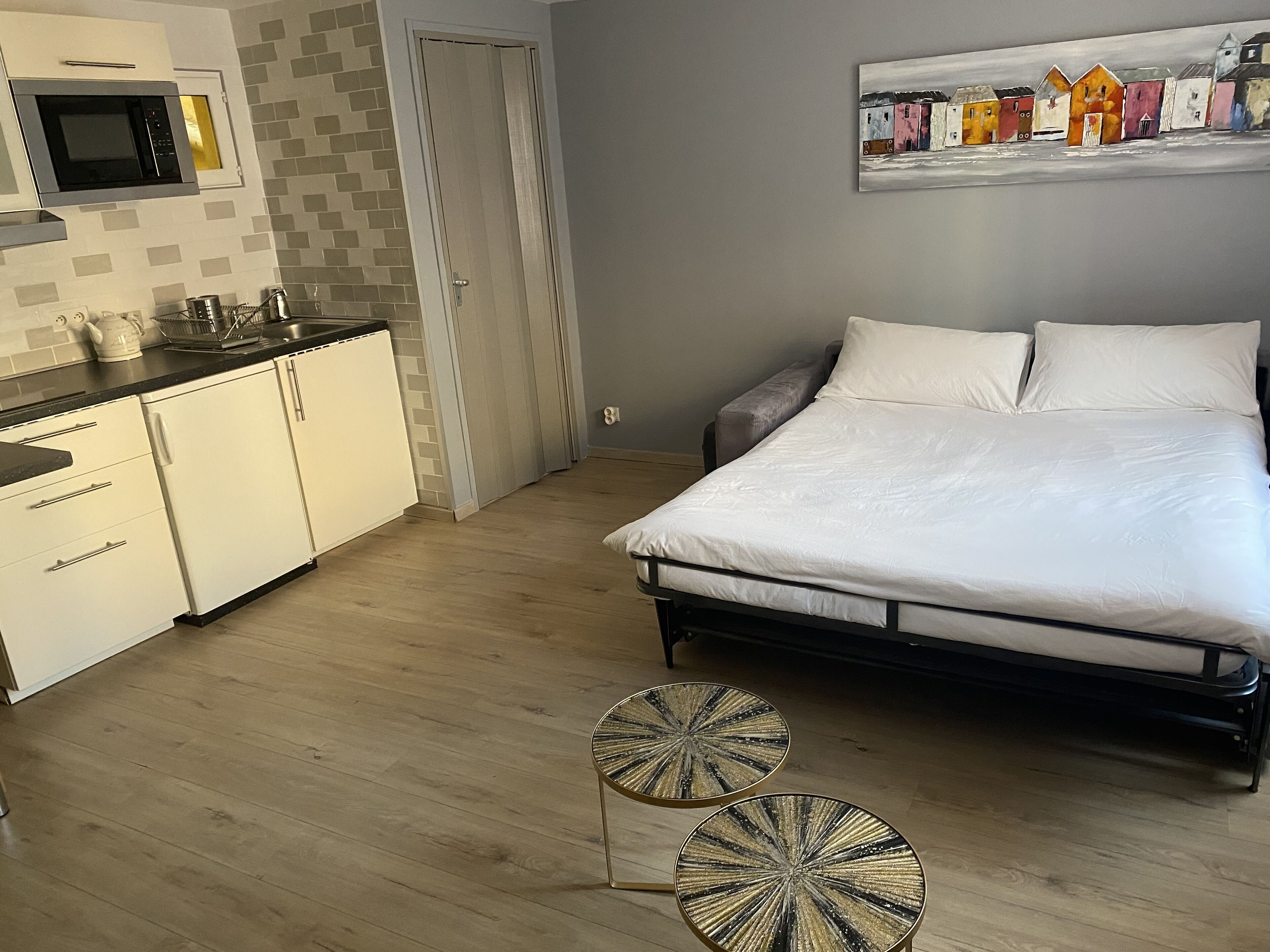 A bedroom with a bed, a nightstand, and a painting on the wall.