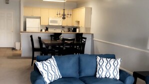 A living room with a blue sofa, a black coffee table, and patterned throw pillows. - Amazing Clean 4th floor condo, newly furnished, new paint,carpet,privet  Wifi,  (Myrtle Beach)