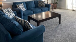 A living room with a blue sofa set, a coffee table, a ceiling fan, and a large window with blinds. - Amazing Clean 4th floor condo, newly furnished, new paint,carpet,privet  Wifi,  (Myrtle Beach)