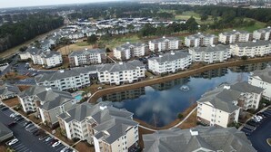 A residential area with apartment buildings, a parking lot, and a body of water. - Amazing Clean 4th floor condo, newly furnished, new paint,carpet,privet  Wifi,  (Myrtle Beach)