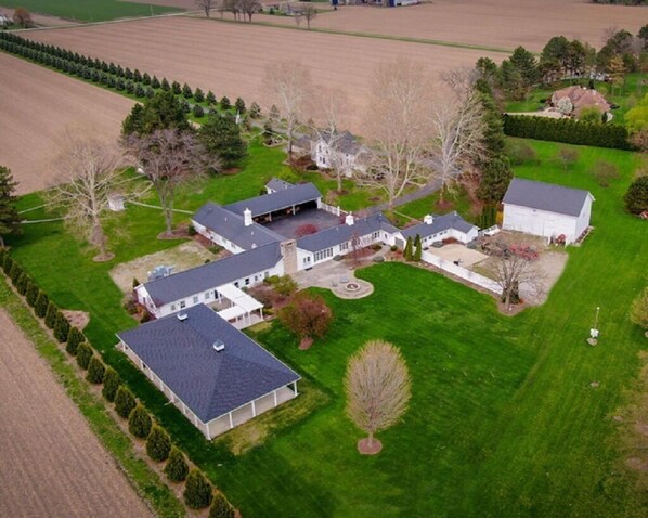 An aerial view of a large estate with multiple buildings, expansive fields, and a well-maintained lawn.