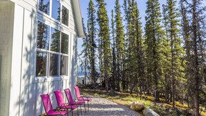 A building with large windows and a gravel patio with pink chairs. - Alpenglow Ridge Fireweed (Healy)