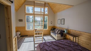 A room with a loft bed, a ladder, a sofa, and a small table. - Alpenglow Ridge Fireweed (Healy)