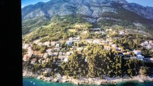 Un pueblo costero con casas construidas en una ladera, rodeado de vegetación y montañas.