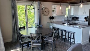 Una cocina moderna con armarios blancos, una isla central y un comedor con una mesa redonda y sillas.