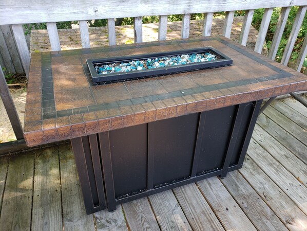 A wooden deck with a metal table featuring a glass top.