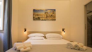 A hotel room with a bed, pillows, a blanket, and towels. - Sammartino suite (Palermo)