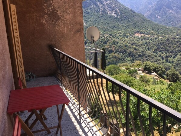 A balcony with a red folding chair, a satellite dish, and a view of a mountainous landscape. - village house Ota (Ota)