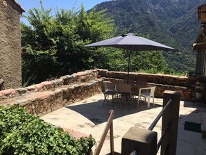 An outdoor patio with stone walls, a table with chairs, and an umbrella. - village house Ota (Ota)