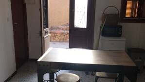 A kitchen with a large table and two stools, a microwave, and a basket on the counter. - village house Ota (Ota)