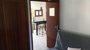 A room with a bed, a wooden wardrobe, and a doorway leading to a kitchen area. - village house Ota (Ota)