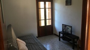 A small, sparsely furnished room with a bed, a small table, and a television. - village house Ota (Ota)