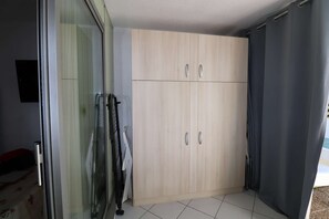 A room with a sliding glass door, a wooden wardrobe, and a tiled floor.