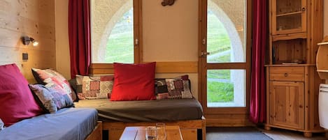 A cozy room with a bed, a wooden bench, a table with a glass and a book, and a cabinet.