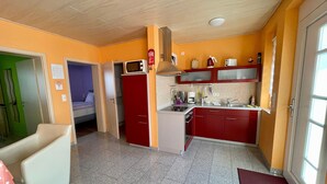 A compact kitchen with red cabinets, a microwave, and a small refrigerator. - Non-smoking vacation apartment 50sqm, no. 1, 2 bedrooms, max. 4 persons - (Rust)