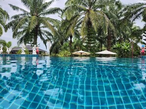 A clear blue pool surrounded by palm trees and umbrellas. - Palmthien Pool Villa Aonang (Krabi)