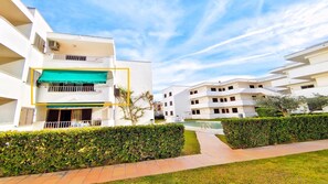 A modern apartment complex with multiple balconies, a swimming pool, and well-maintained greenery.