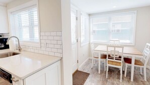 A kitchen with white cabinets, a stainless steel sink, and a window with blinds. - Stylish space, 180ft to beach,parking (Point Pleasant Beach)
