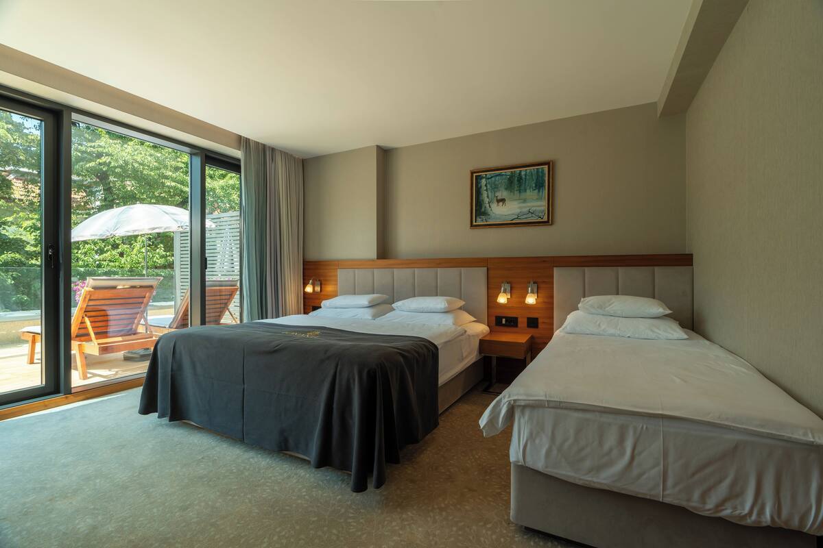 Habitación de hotel con dos camas, un ventanal grande, un cuadro en la pared y vistas al exterior.