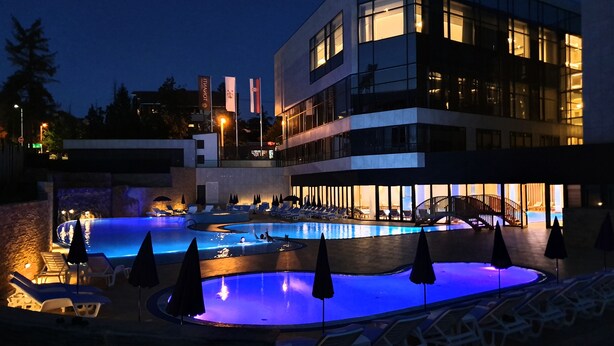Een modern hotel met een zwembad, ligbedden en parasols.