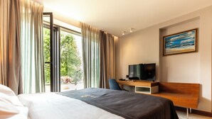 Una habitación de hotel con cama, escritorio y televisión, además de un cuadro en la pared.