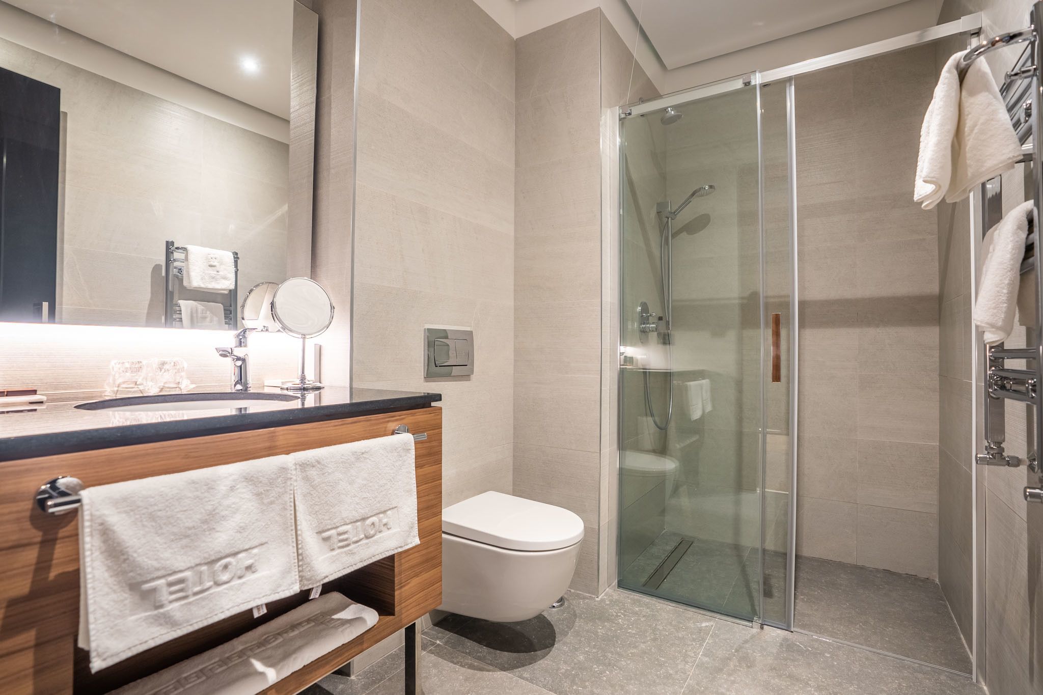 A modern bathroom with a glass shower enclosure, a wooden vanity with a sink, and a toilet.