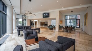 Een ruime lobby met modern meubilair, grote ramen en een hoge plafond.