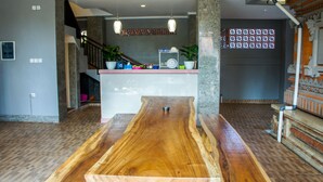A spacious living area with a wooden coffee table, a kitchen island with colorful dishes, and a staircase leading to an upper level. - Dana Homestay (Tibubeneng)