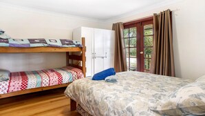 A room with two bunk beds, a single bed, a wardrobe, and a window with curtains.