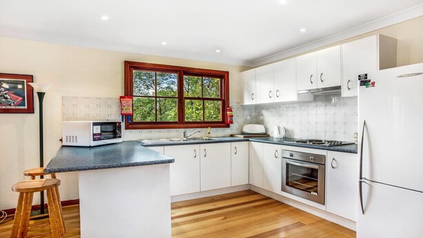 A modern kitchen with white cabinets, a microwave, a stove, and a refrigerator.