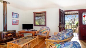 A cozy living room with a fireplace, wicker furniture, a television, and a door leading to an outdoor area.