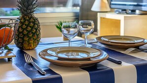 A dining table set with plates, cutlery, and glasses, with a pineapple and an orange basket on the left. - Maison Port En Dro by Interhome (Carnac)