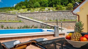 A pool area with lounge chairs and a bowl of fruit.