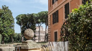A rooftop terrace with a stone balustrade, a wicker chair, and a potted plant. - Domus Alberico (Rome)