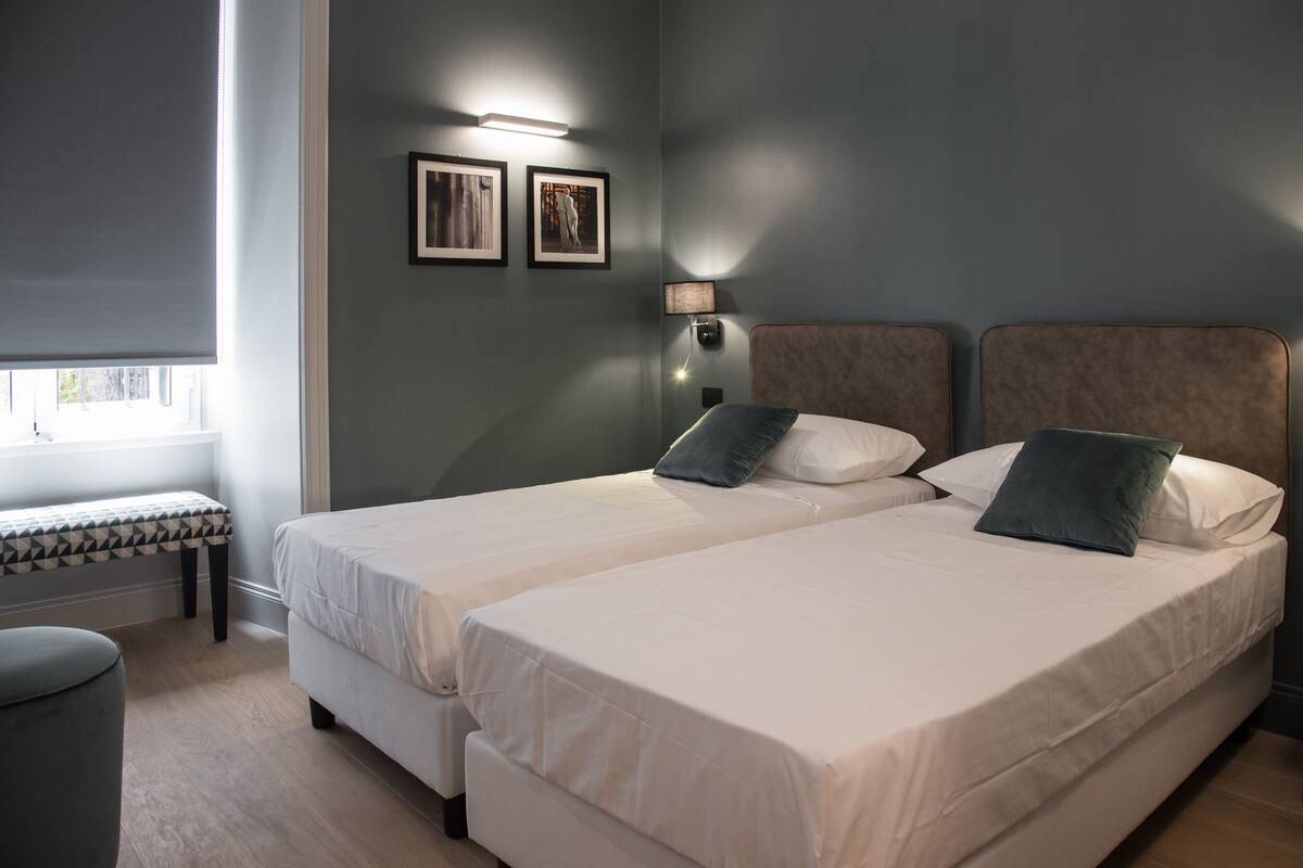 Un dormitorio con dos camas, un banco y dos cuadros en la pared.