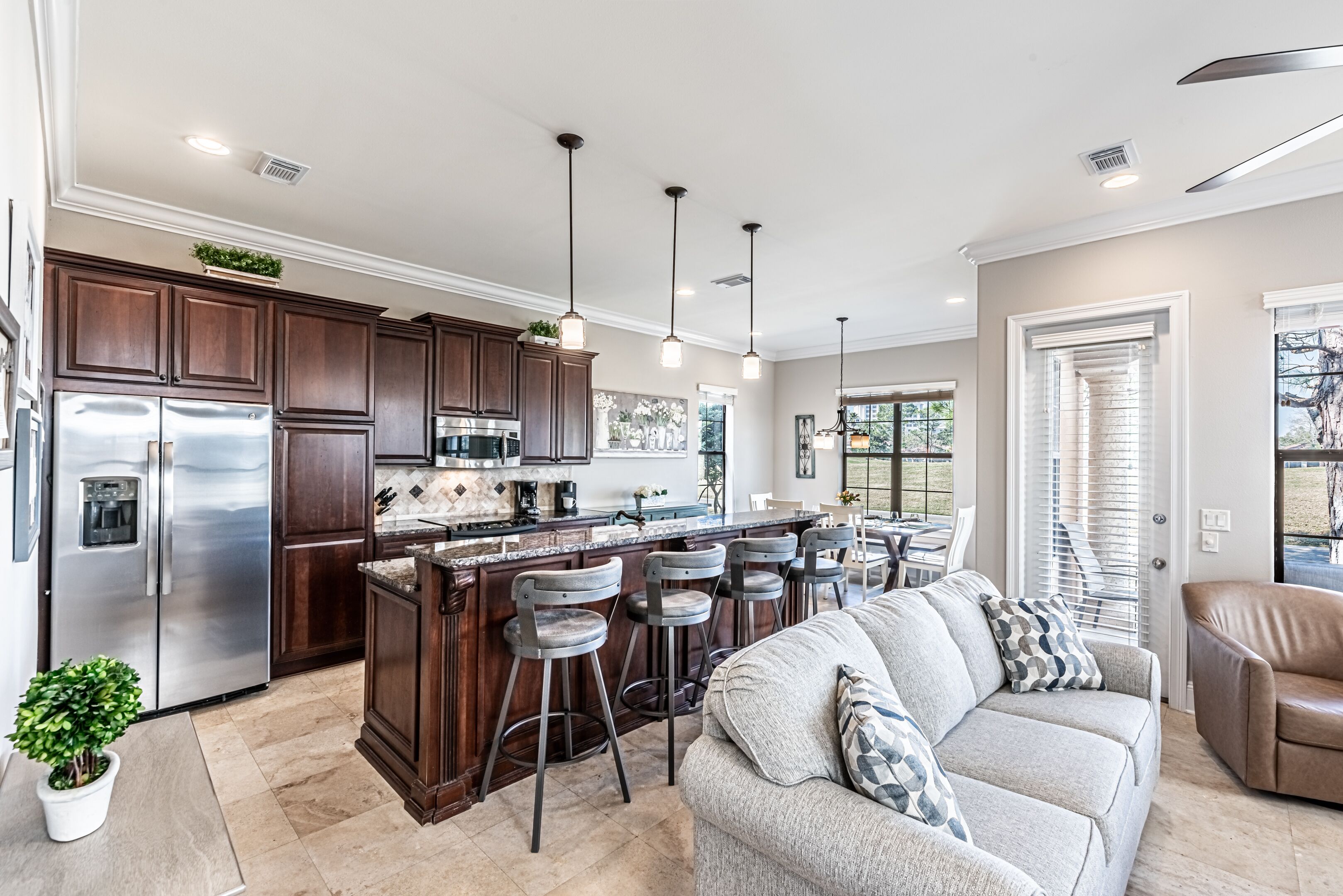 A modern kitchen with dark wood cabinets, stainless steel appliances, and a central island with bar stools.