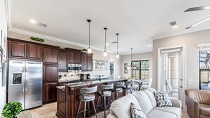 A modern kitchen with dark wood cabinets, stainless steel appliances, and a central island with bar stools. - Pet Friendly ~ Two Golf Carts ~ Golf Course View (Miramar Beach)
