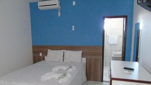 A hotel room with a bed, a bedside table, a mirror, and an air conditioning unit on the wall. - Pousada Solar da Lagoa Baixio (Esplanada)