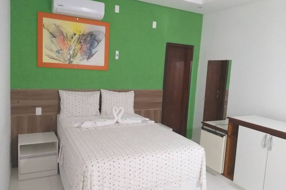A neatly arranged bedroom with a bed, a nightstand, a desk, and a wardrobe.