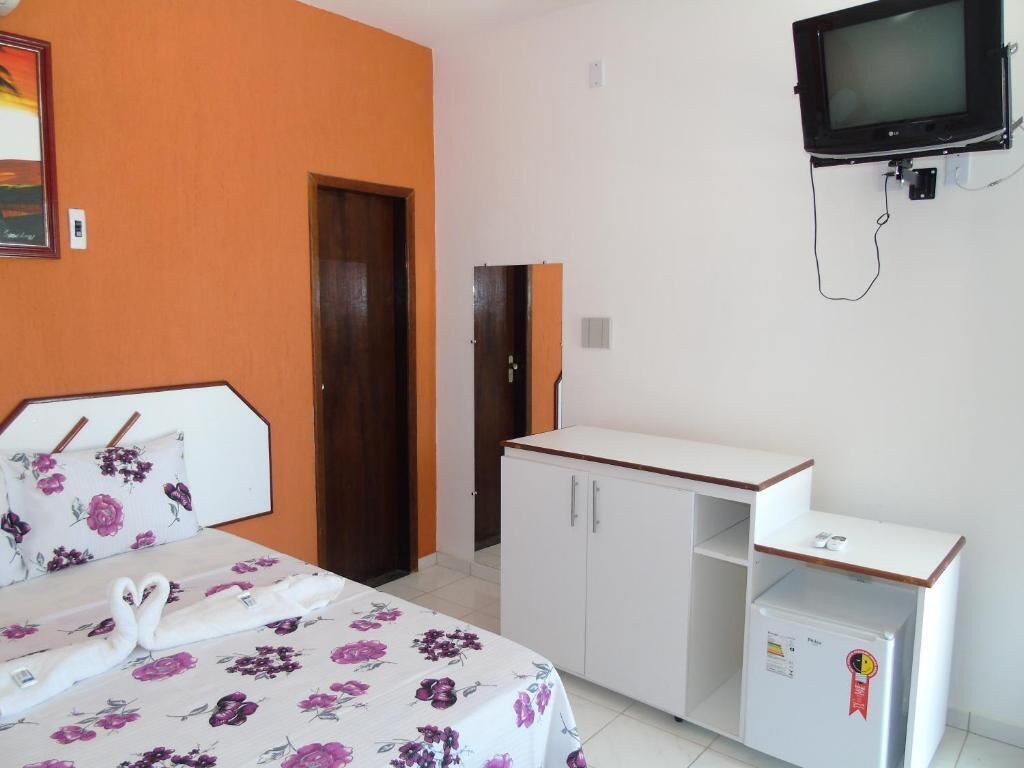 Une chambre d’hôtel équipée d’un lit, d’un bureau, d’une télévision et d’un réfrigérateur.