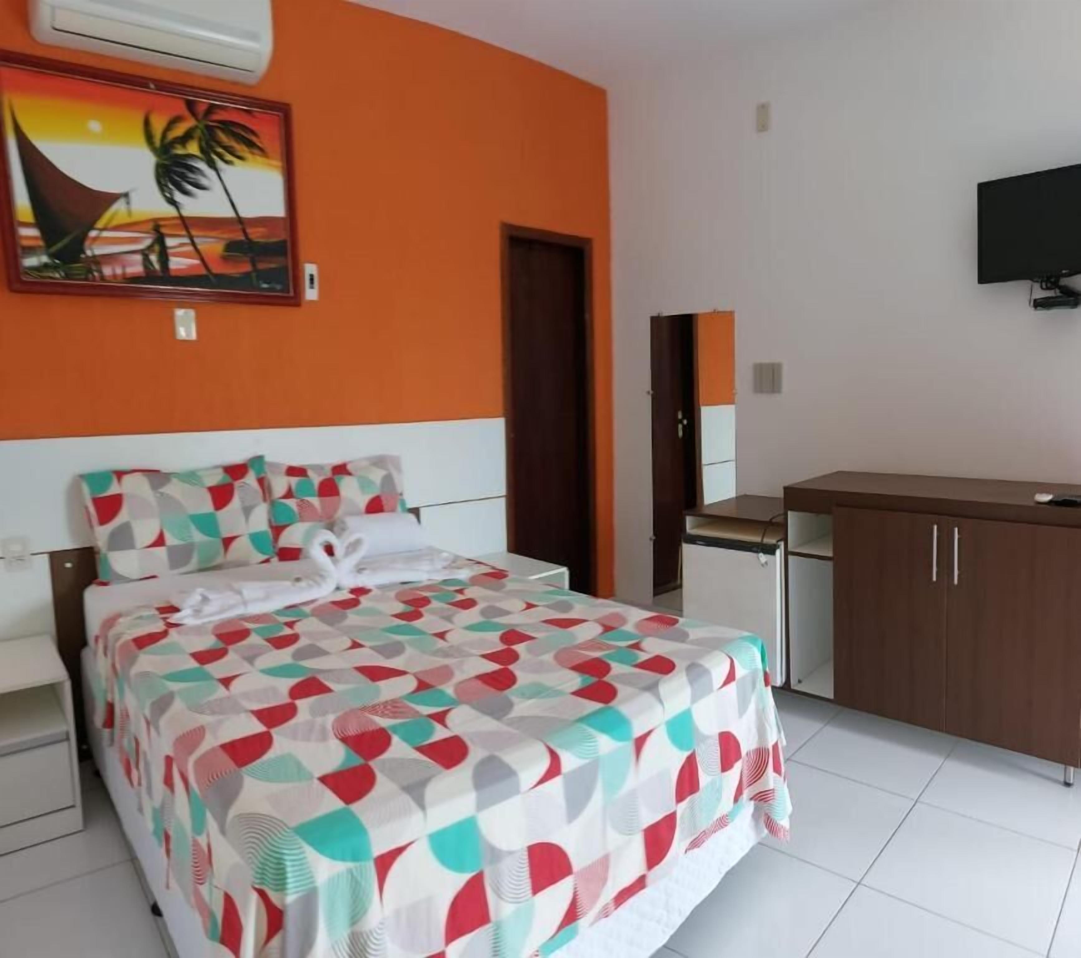 Une chambre d’hôtel avec un lit, un bureau, une chaise, une télévision et un tableau au mur.